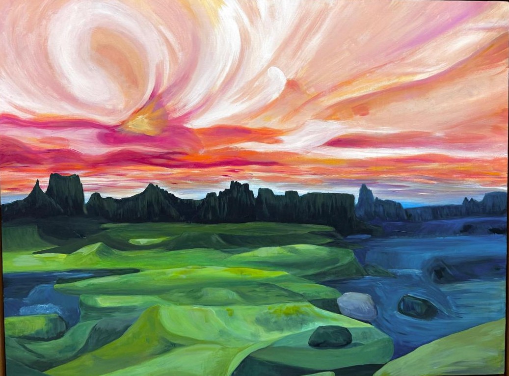 Swirling pink and orange sunset sky over dark rock spires, green hills and blue water